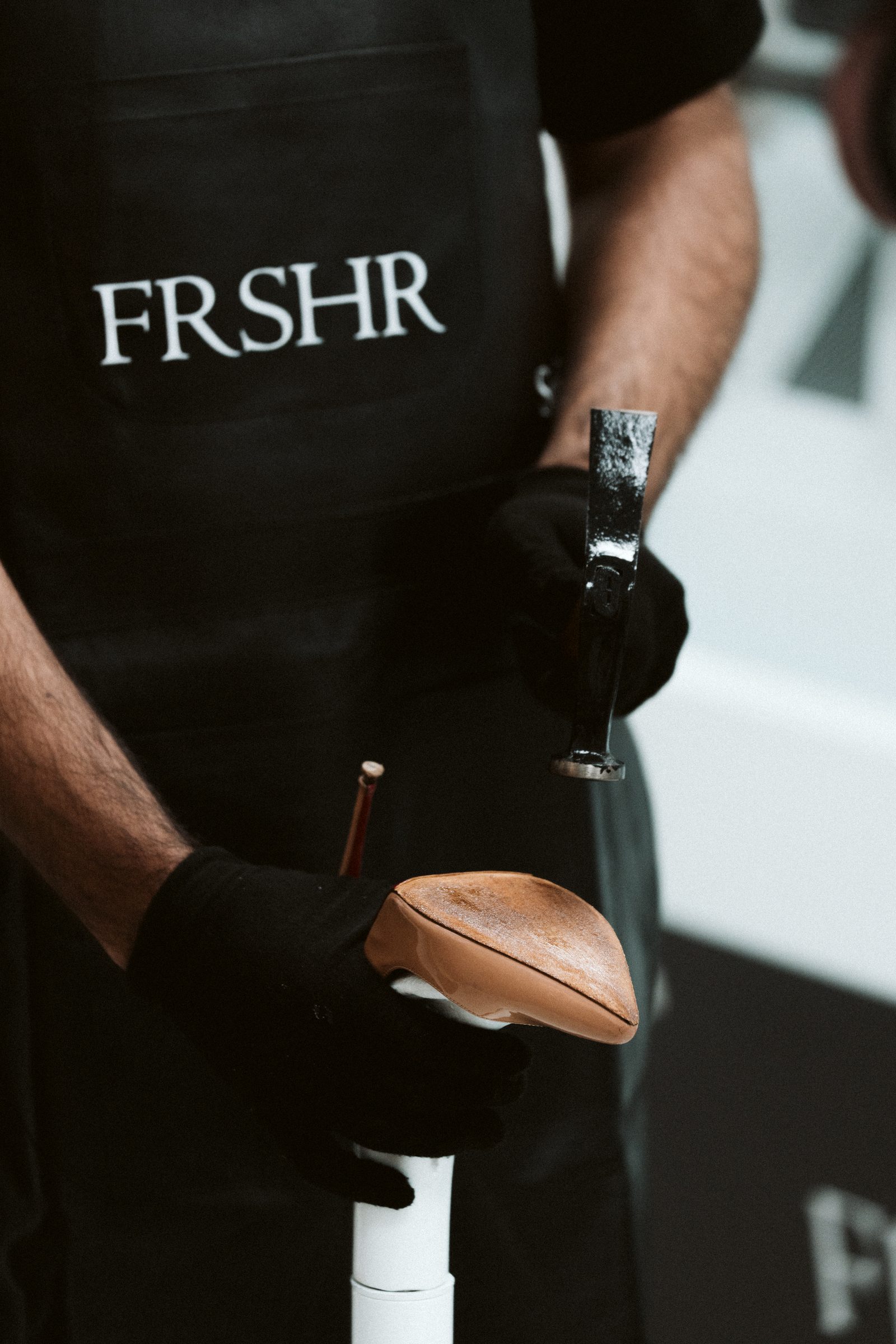 A FRSHR technician working a hammer along the sole of a shoe